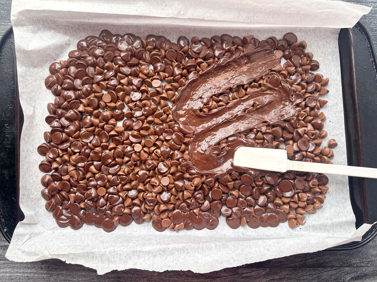 parchment covered baking sheet with melted chocolate being spread