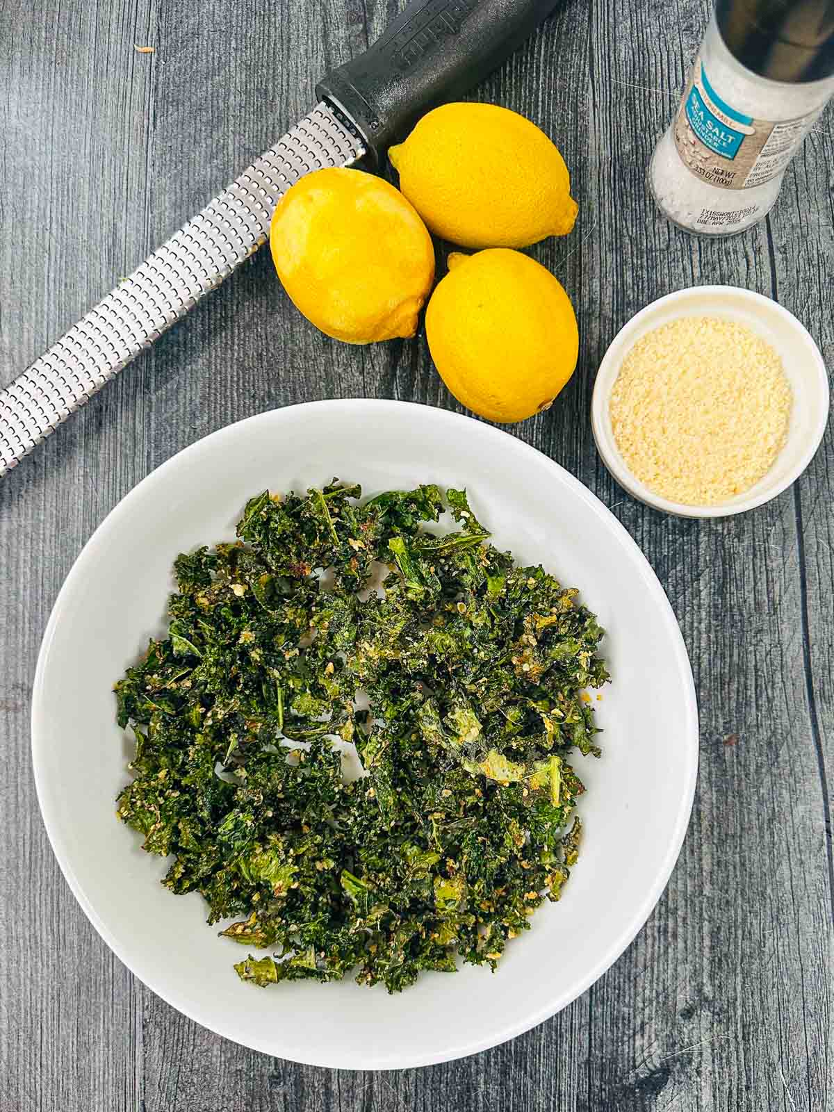 aerial view of bowl of kale chips and fresh lemons and parmesan cheese