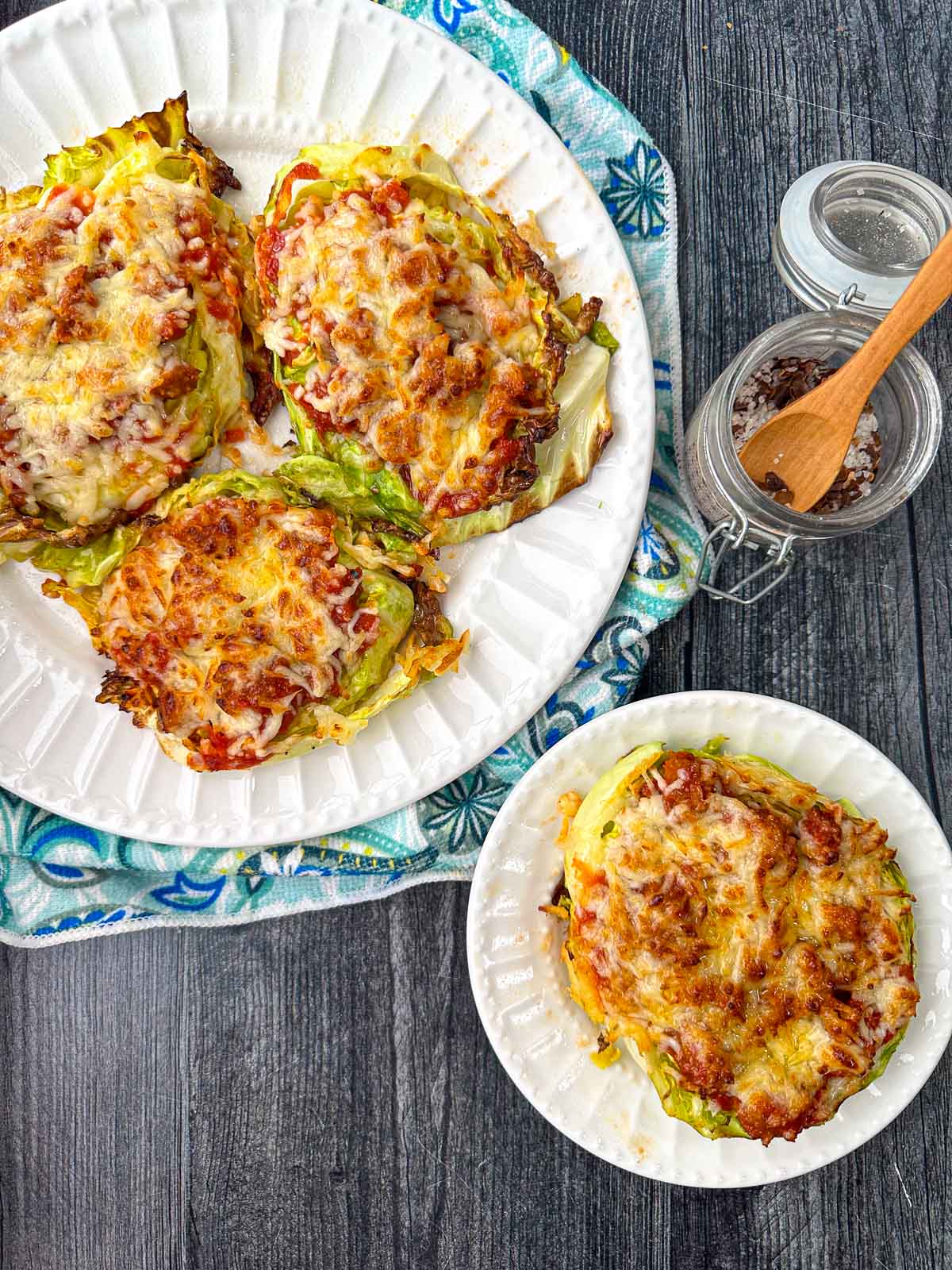 aerial view of white plates with air fryer cabbage steaks topped with meat sauce and cheese