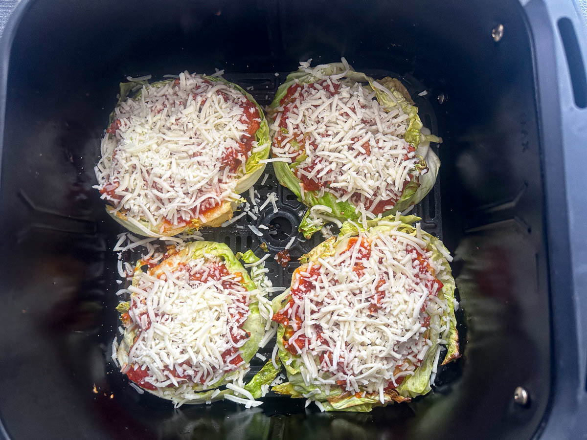 air fryer basket with 4 cabbage pizzas ready to bake