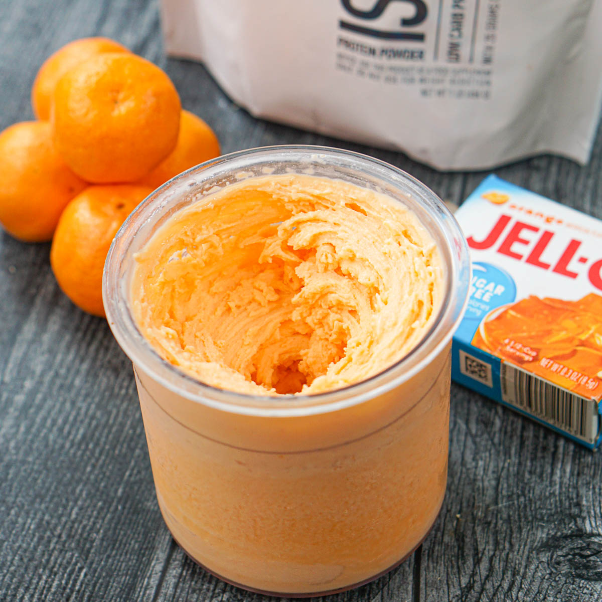low carb high protein creamsicle ice cream in a pint container with jello mix and oranges in the background