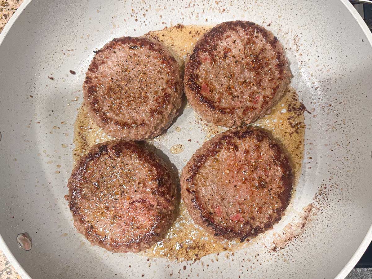 pan with 4 burgers browned