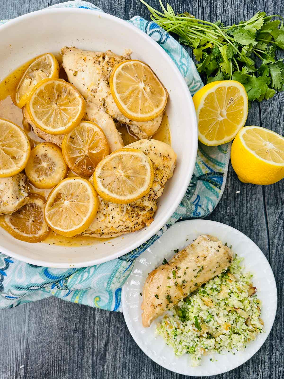 aerial view of white bowl and plate with slow cooker greek chicken and fresh lemons and parsley