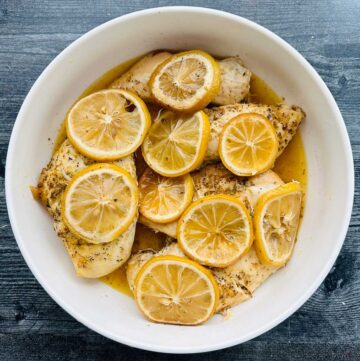 white bowl with slow cooker Greek chicken with lemon slices on top