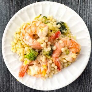 white plate with parmesan pearl couscous with shrimp