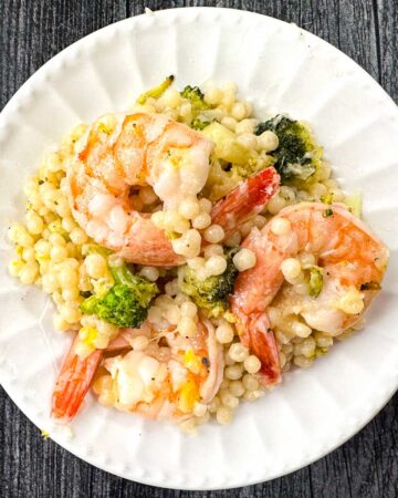 white plate with parmesan pearl couscous with shrimp