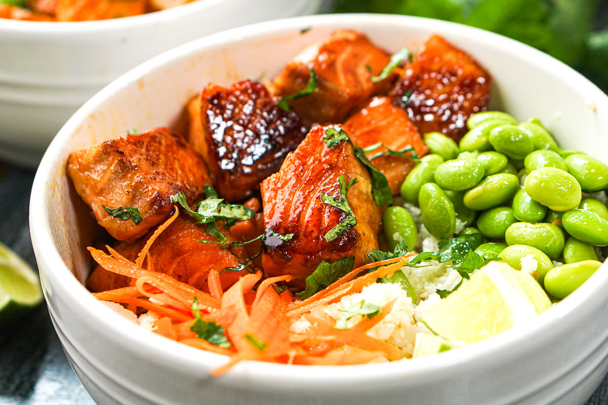 closeup fo a bowl with rice, soy beans, carrot and asian salmon