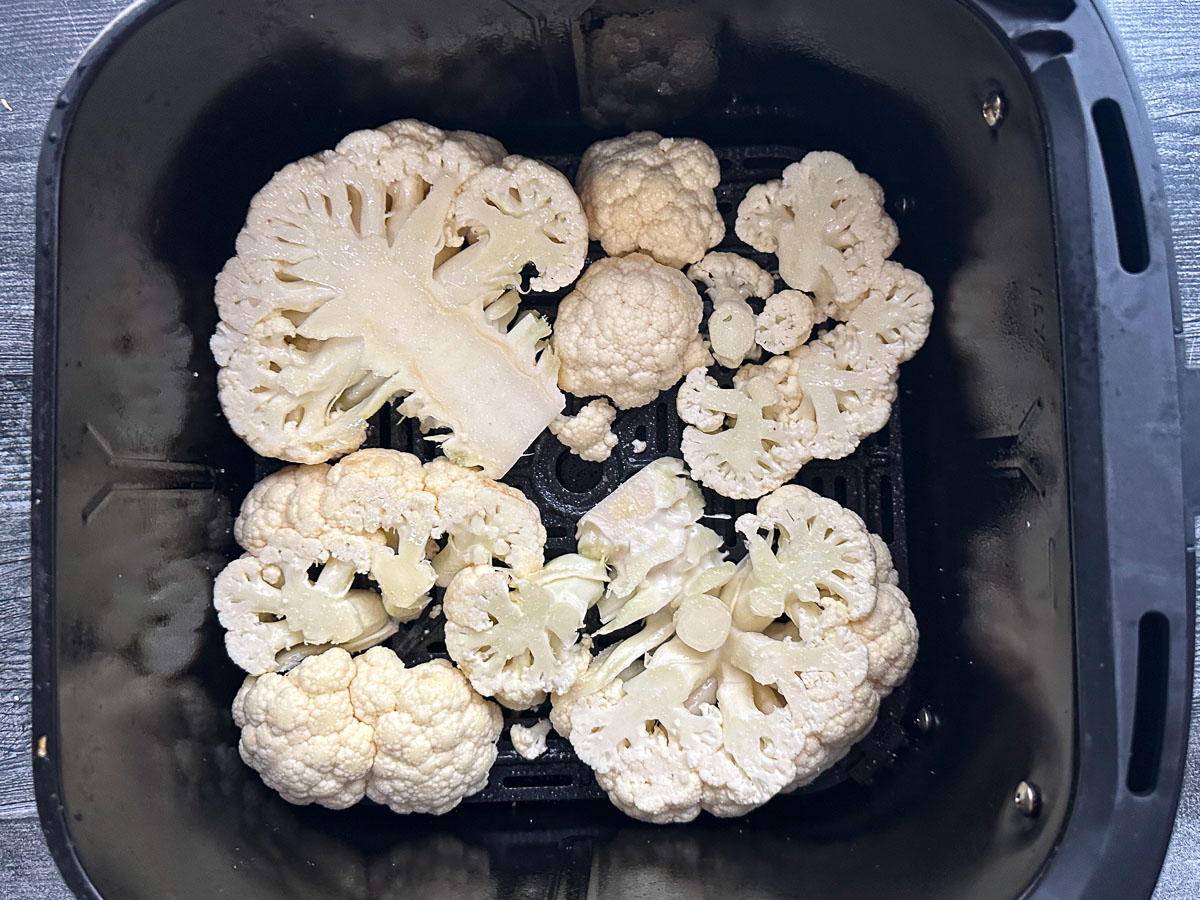 air fryer basket with raw pieces of cauliflower