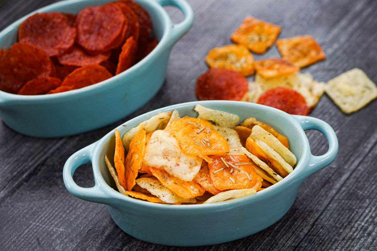 closeup of a bowl of keto cheese chips and pepperoni chips in the background
