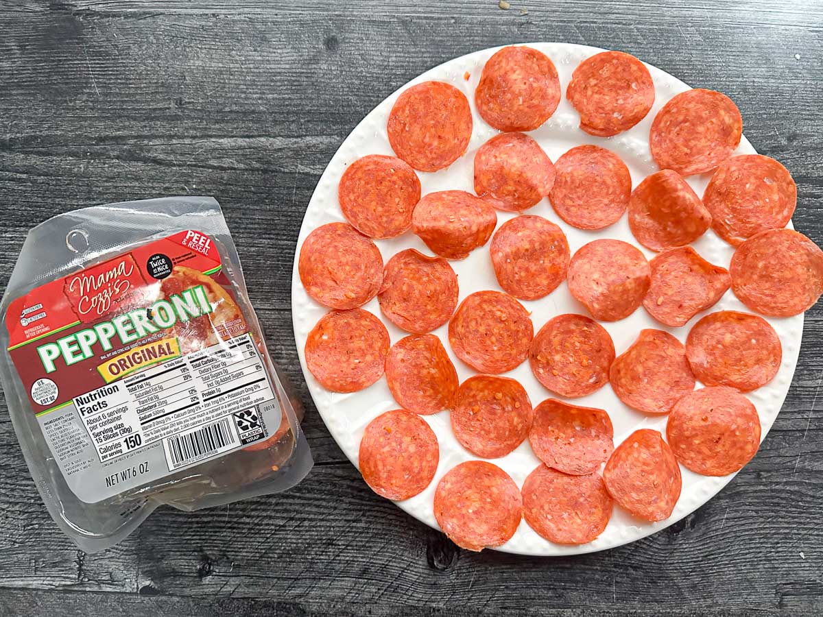 white plate with pepperoni slices on it waiting to microwave