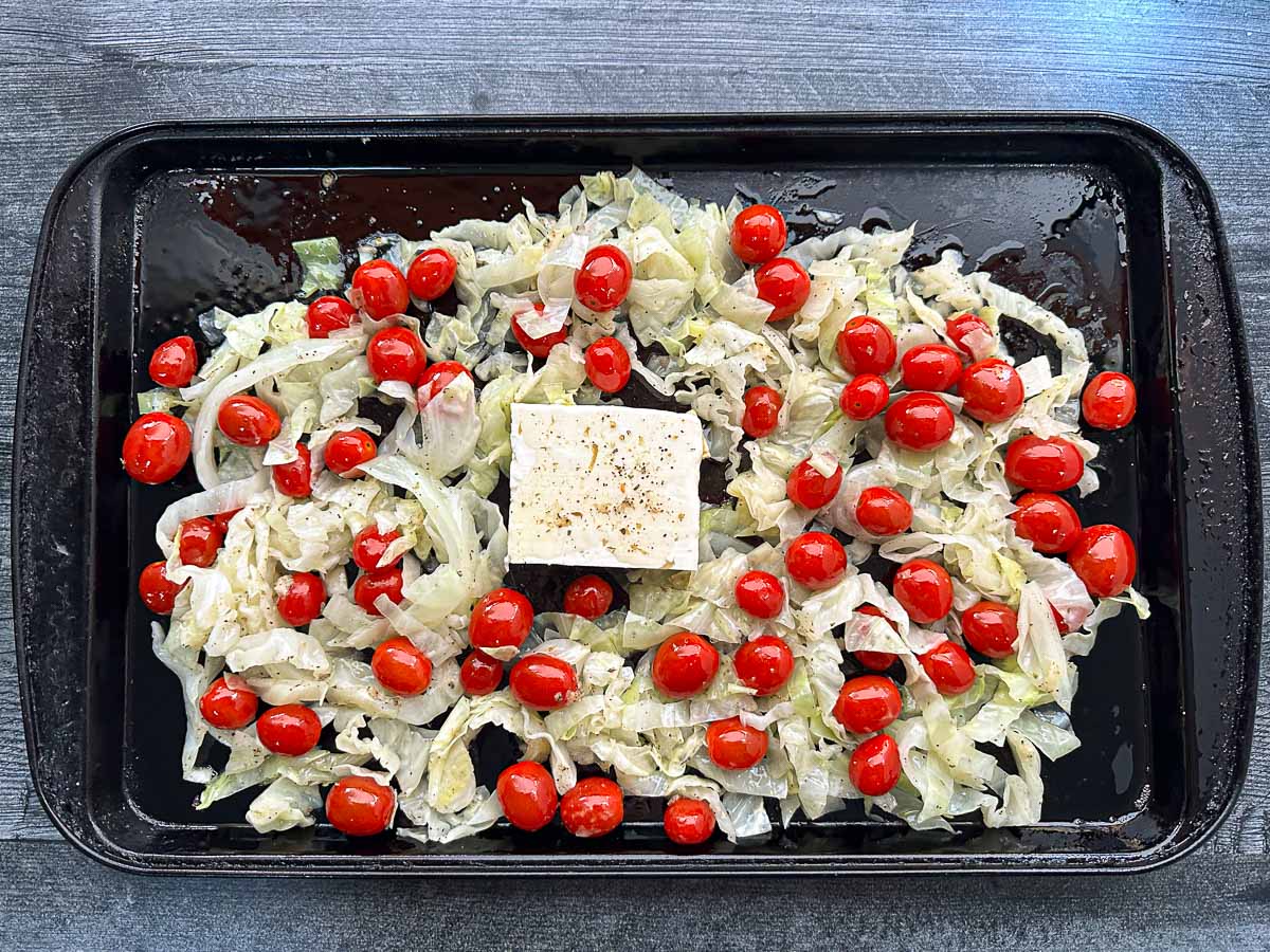baking sheet with raw cabbage, tomatoes and black of feta