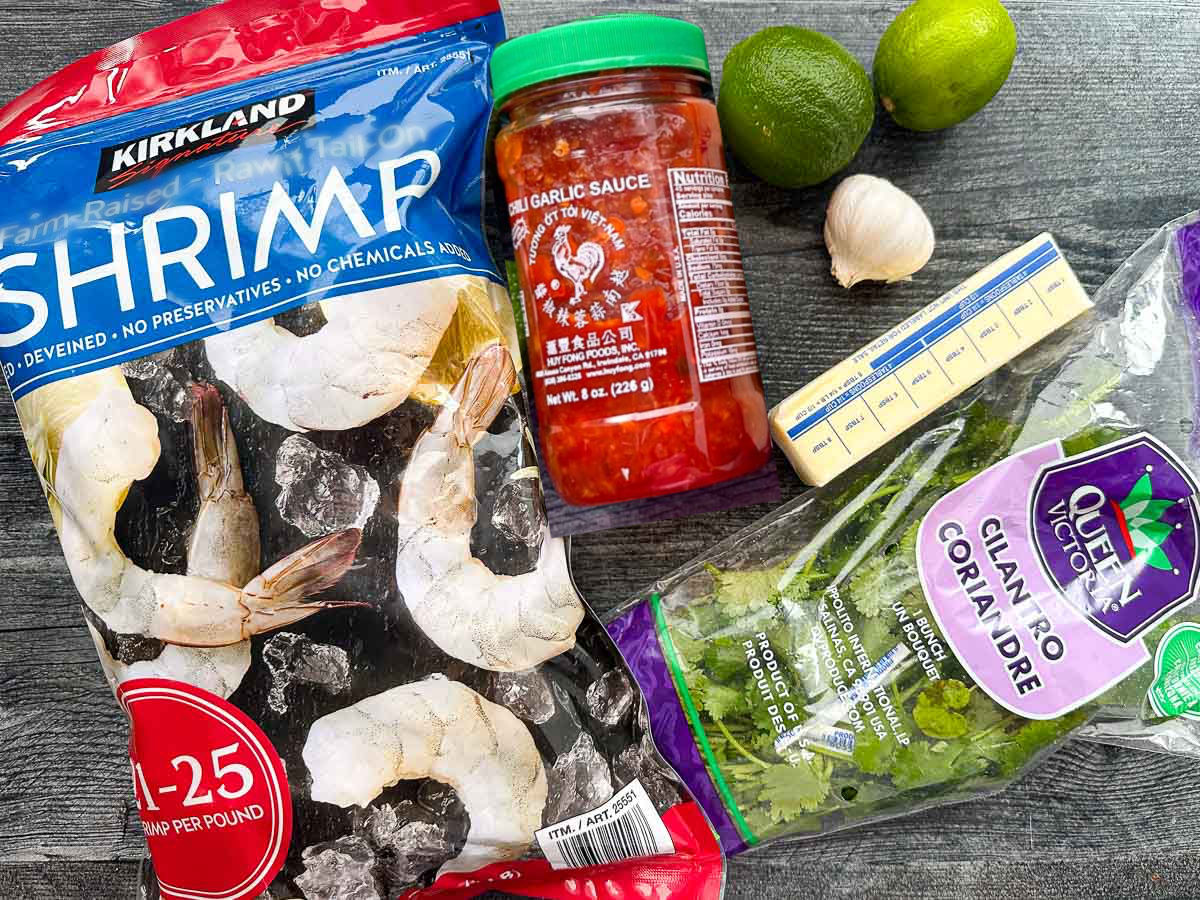 recipe ingredients - raw shrimp, chili garlic sauce, garlic, butter, limes and cilantro