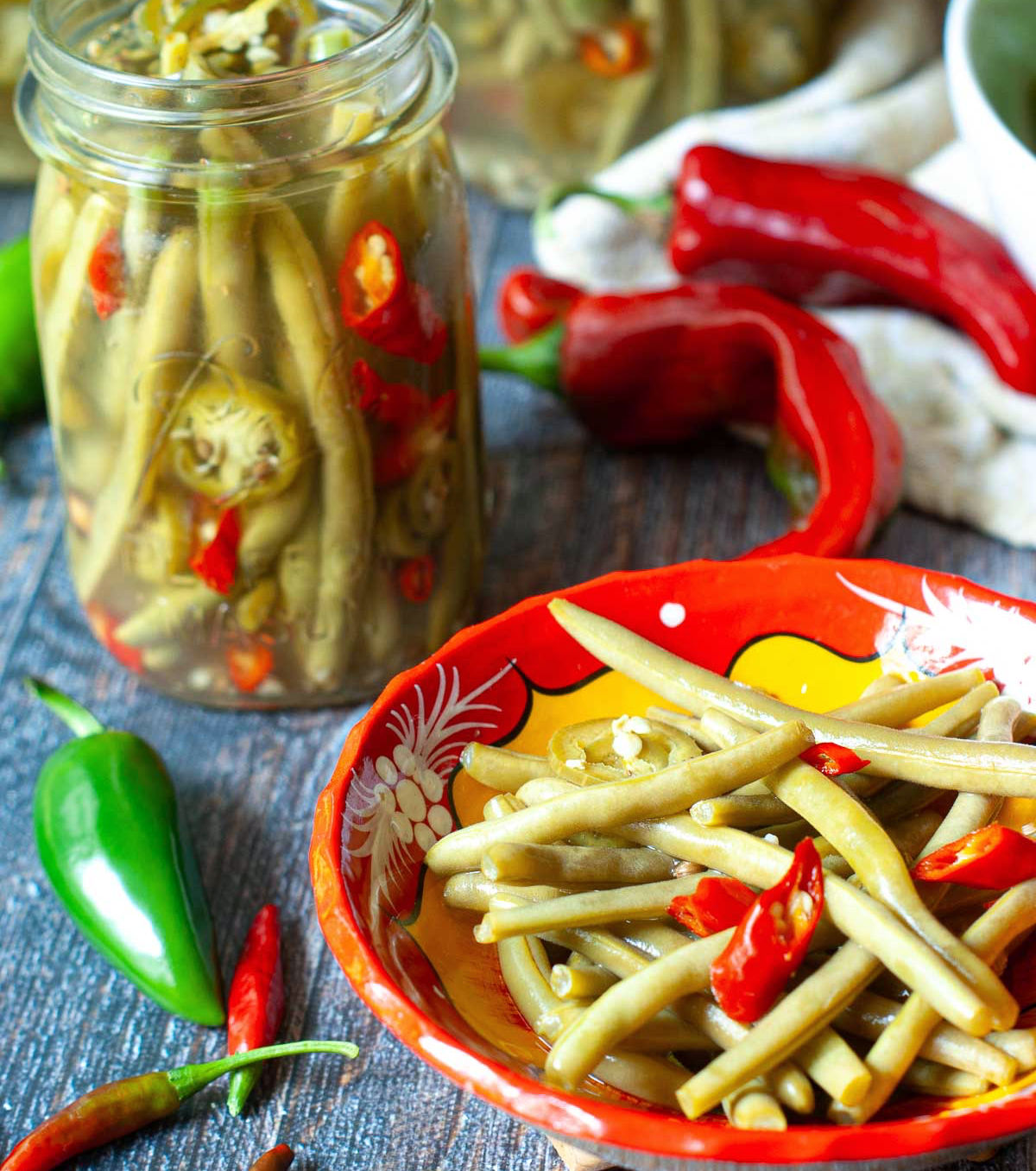 Closeup of a bowl of pickled veggies and a the jars in the background.