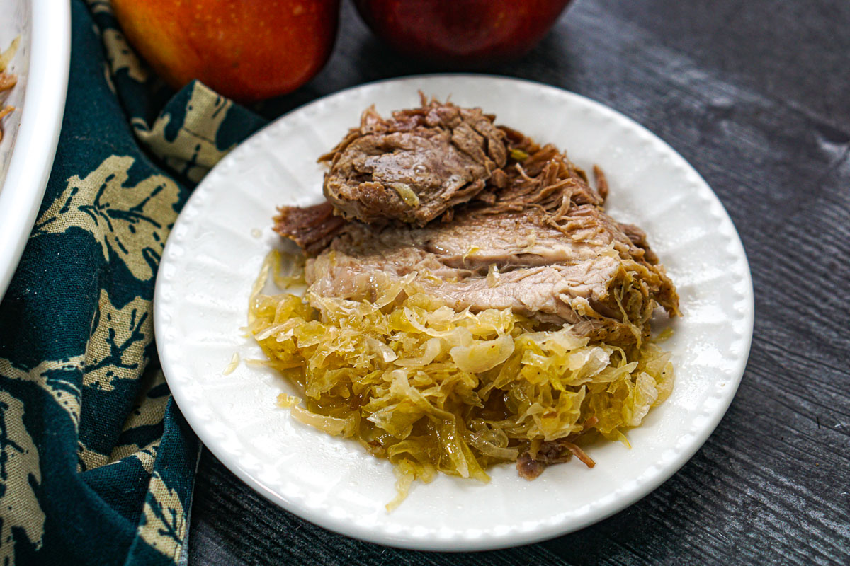 A white plate with a slice of the roast and sauerkraut.
