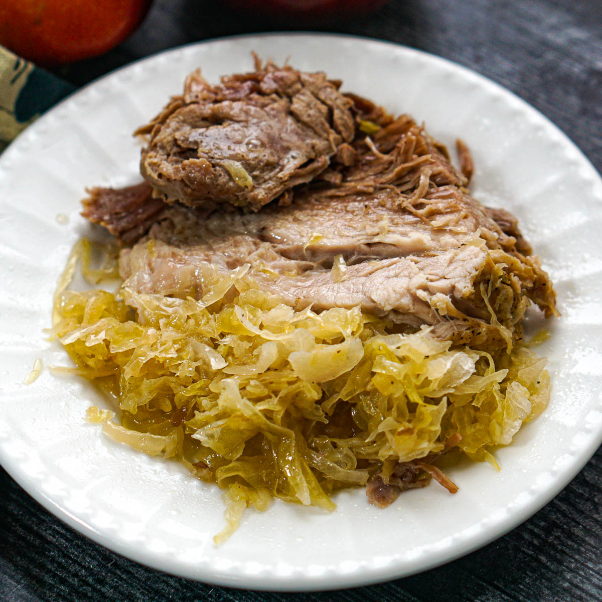 A white plate with Instant Pot pork and sauerkraut.