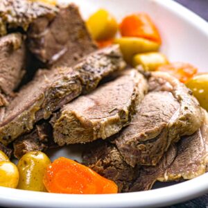 Closeup of a platter of Instant Pot leg of lamb with potatoes and carrots.