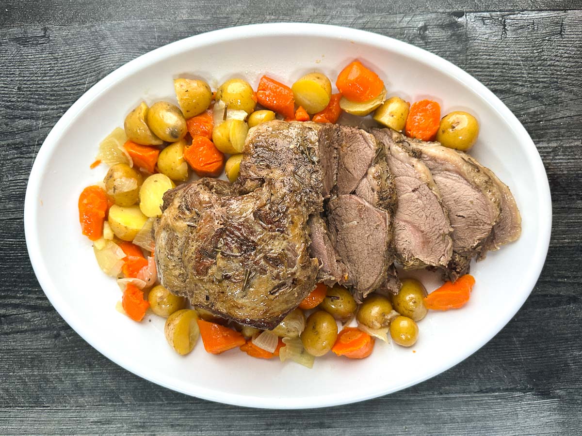 Aerial view of the finished roast dish on a white platter carrots and potatoes.