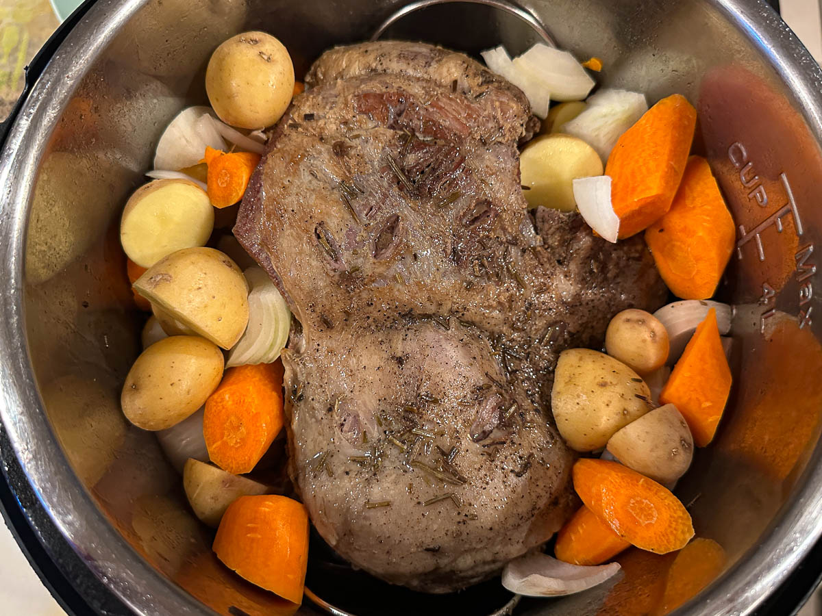 Cooked lamb with raw veggies ready to cook in the pressure cooker.