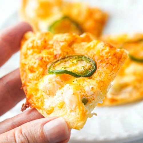 closeup of fingers holding one of the shrimp nachos