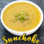 Closeup of a bowl of Jerusalem artichoke soup with green onions on top and text overlay.