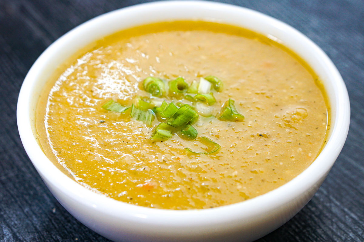 Closeup of a bowl of Jerusalem artichoke soup with green onions on top.