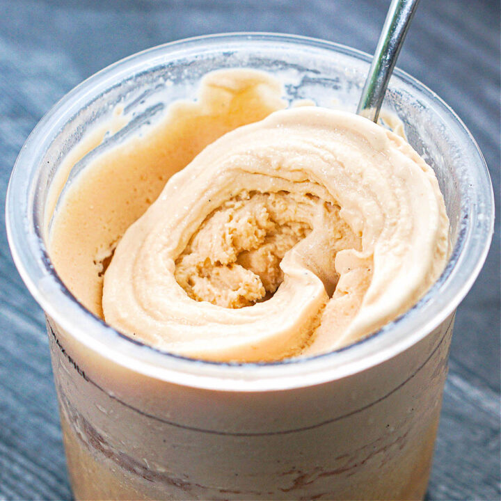 Closeup of a pint container with some Ninja Creami vanilla ice cream and a spoon.