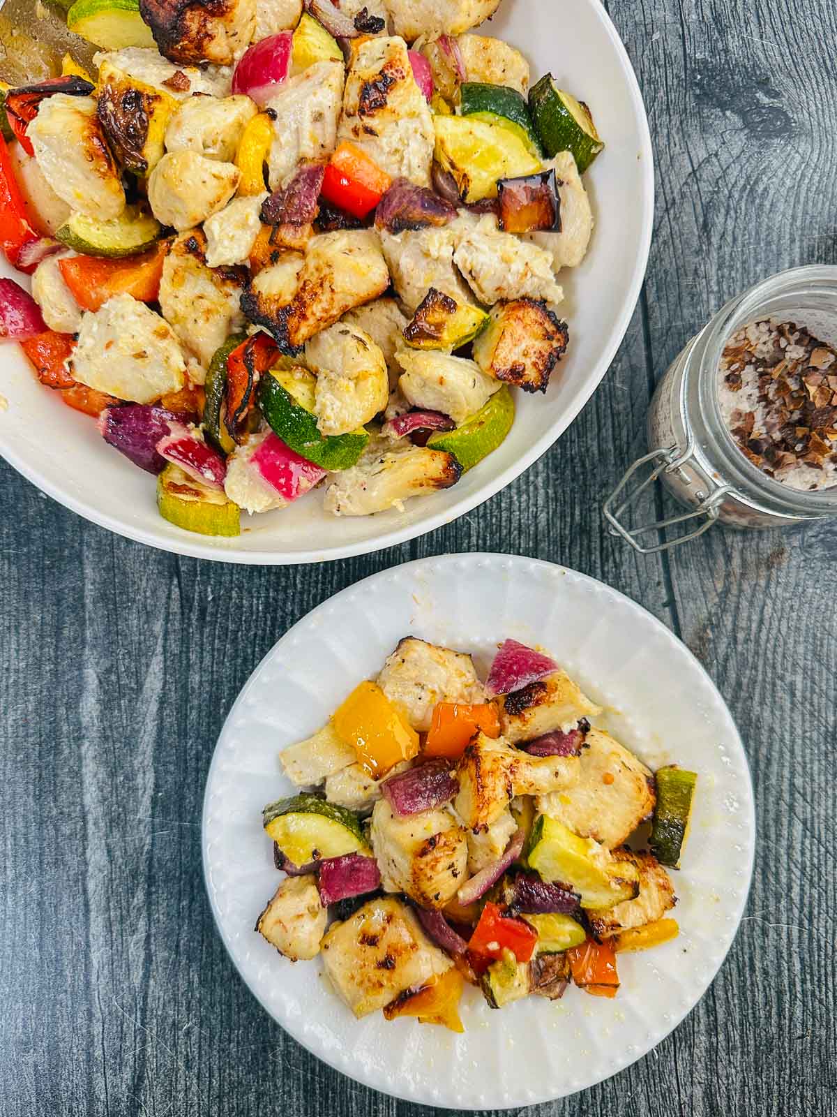 Aerial view of a white bowl and plate with the air fryer chicken bites with vegetables.