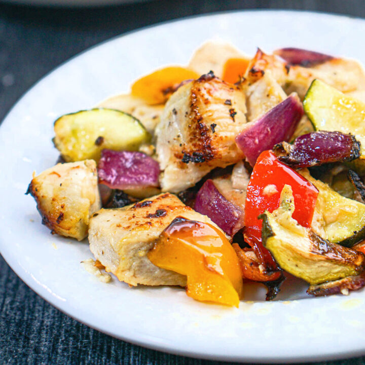 Closeup of a white plate with a serving of low carb air fryer chicken bites and vegetables.