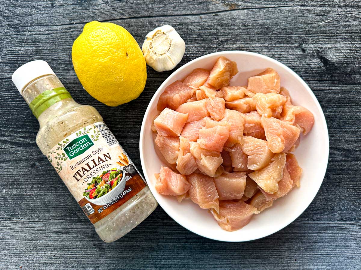 Recipe ingredients I used - bowl of chopped raw chicken breast, a bottle of Italian dressing, 1 lemon and fresh garlic cloves.