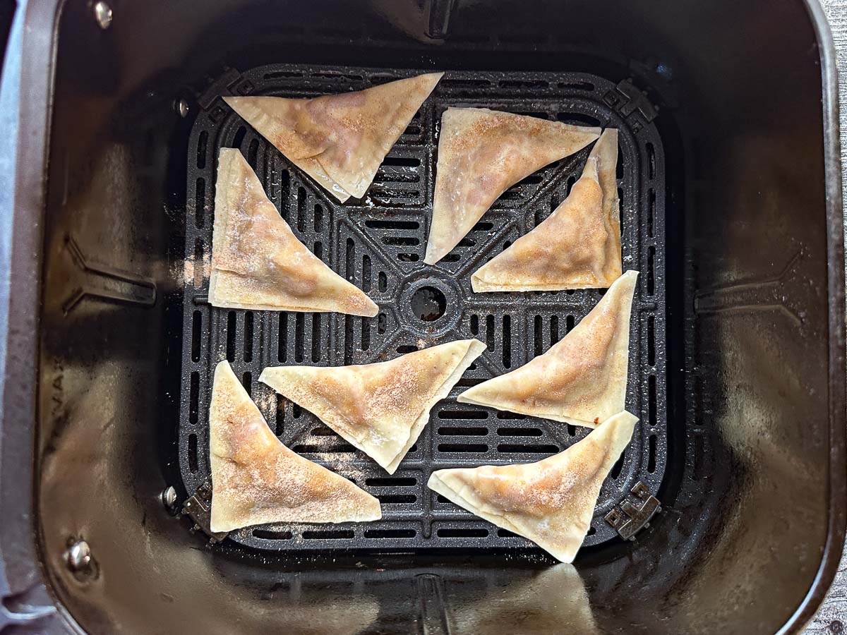 Air fryer basket with the wontons ready to bake.