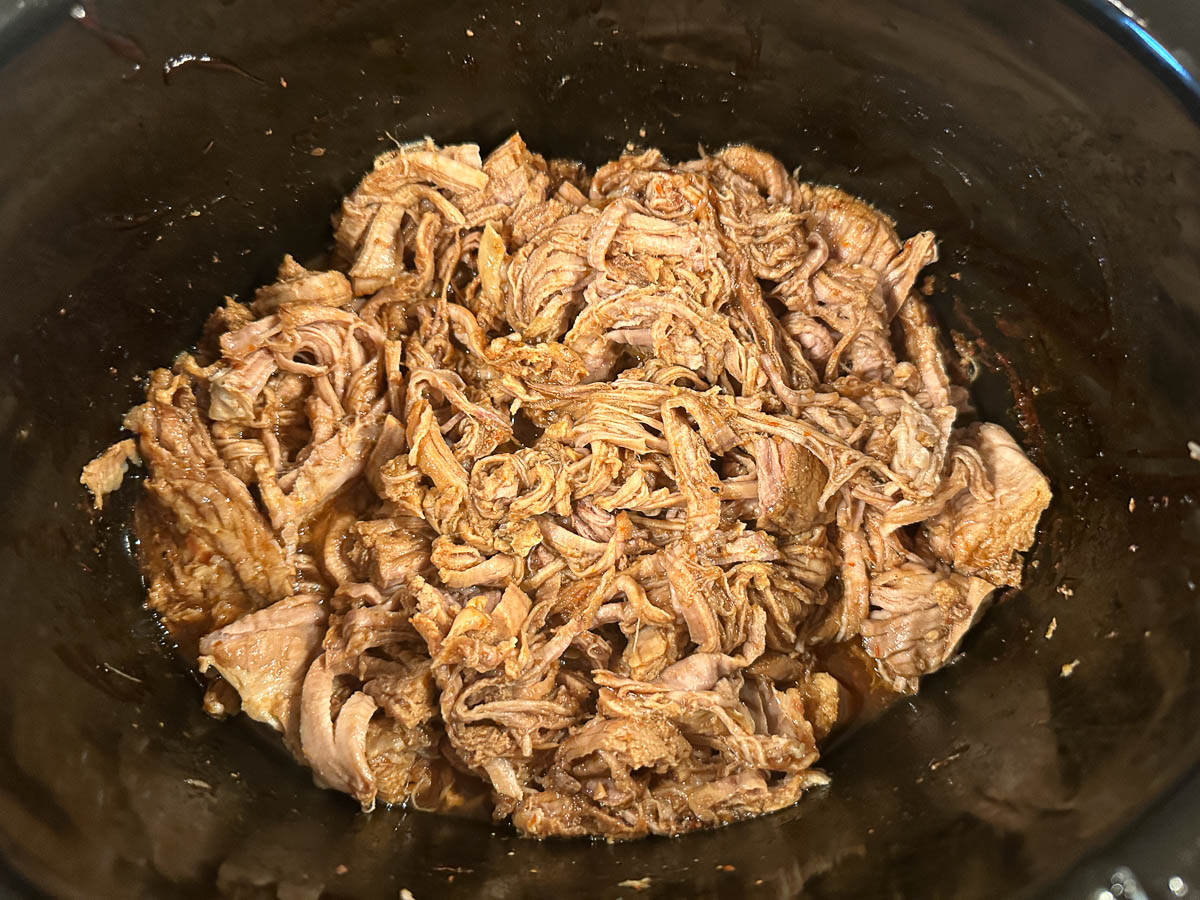 Slow cooker with the finished pulled pork tenderloin.