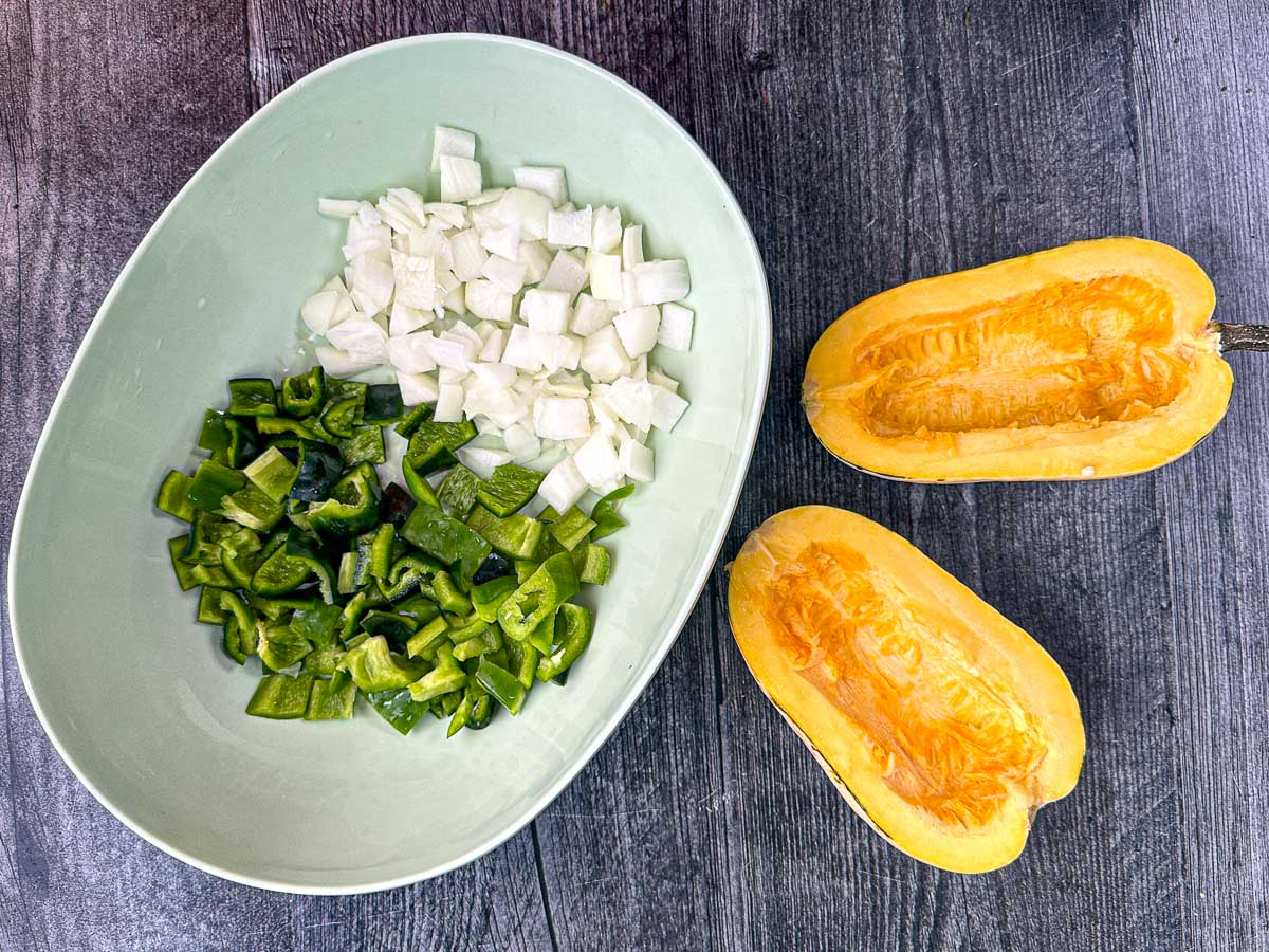 Recipe ingredients - a delicata squash cut in half and deseeded, chopped onions and chopped peppers.