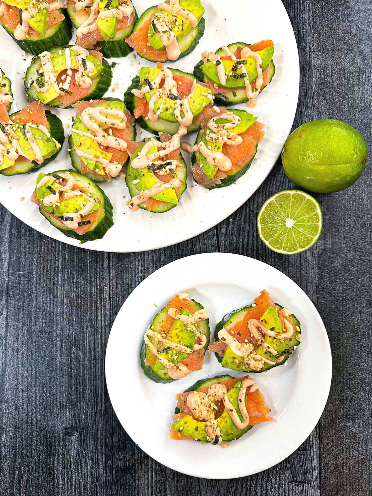 Aerial view of white plates with the cucumber  salmon bites and 2 fresh limes.