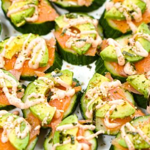 Closeup of a plate full of keto cucumber salmon bites with spicy mayo sauce.