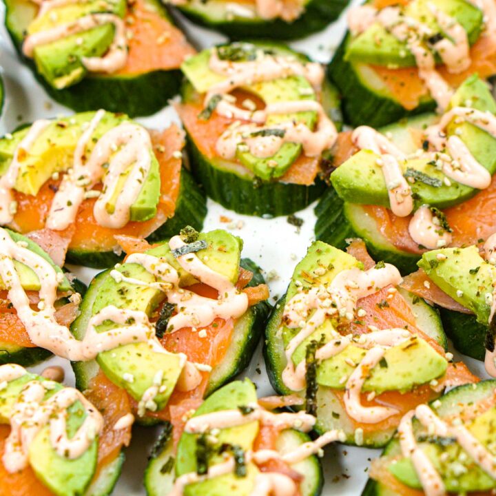 Closeup of a plate full of keto cucumber salmon bites with spicy mayo sauce.