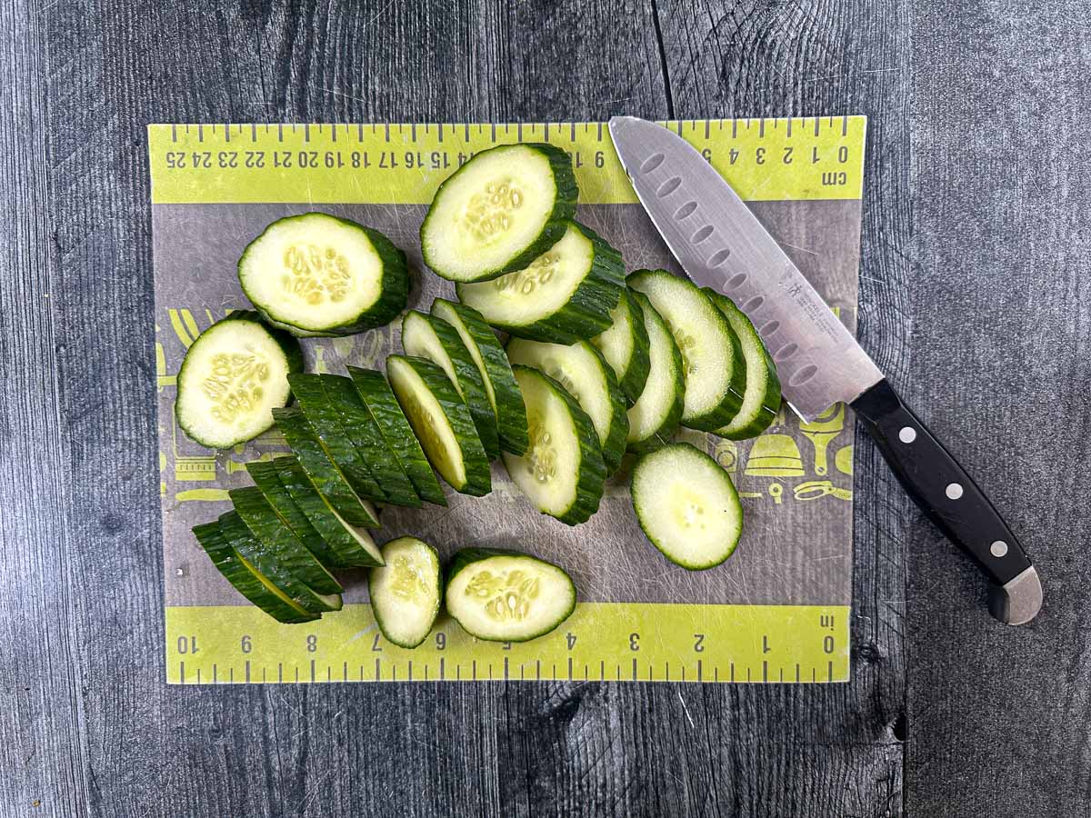 Cucumber slices on a cutting board with knife.