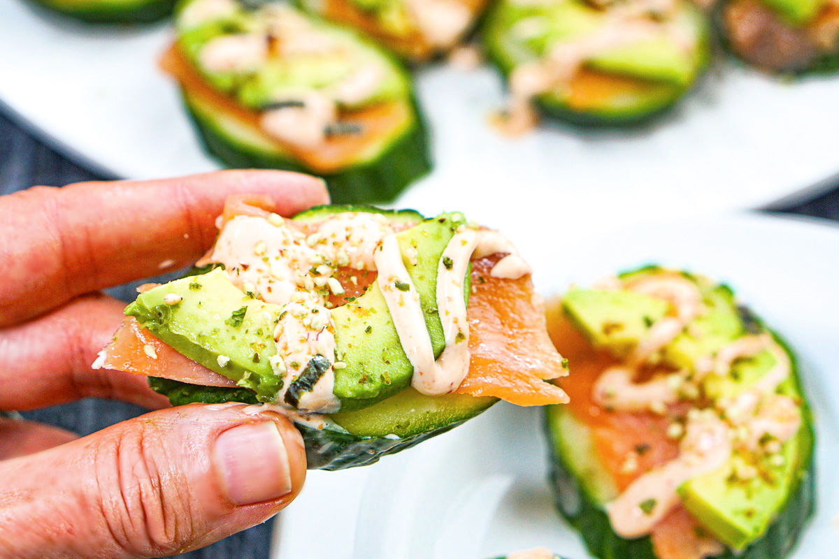 Fingers holding one of pieces cucumber sushi bites. 