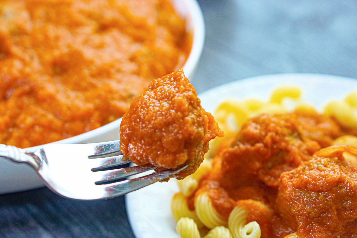 Closeup of a fork with a veggie meatballs on it that was mixed with pasta sauce.