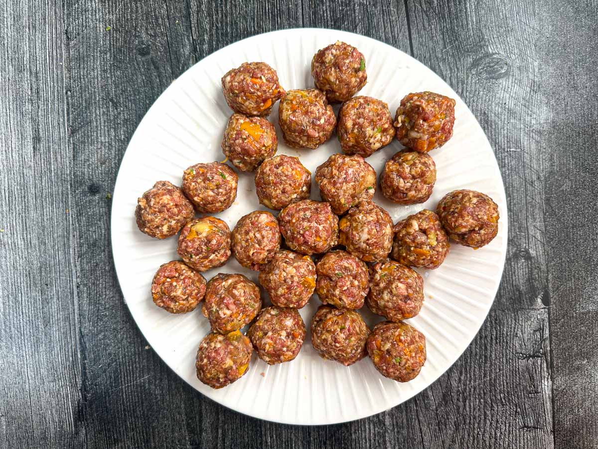 White plate with the raw mixture made into meatballs with hidden veggies.