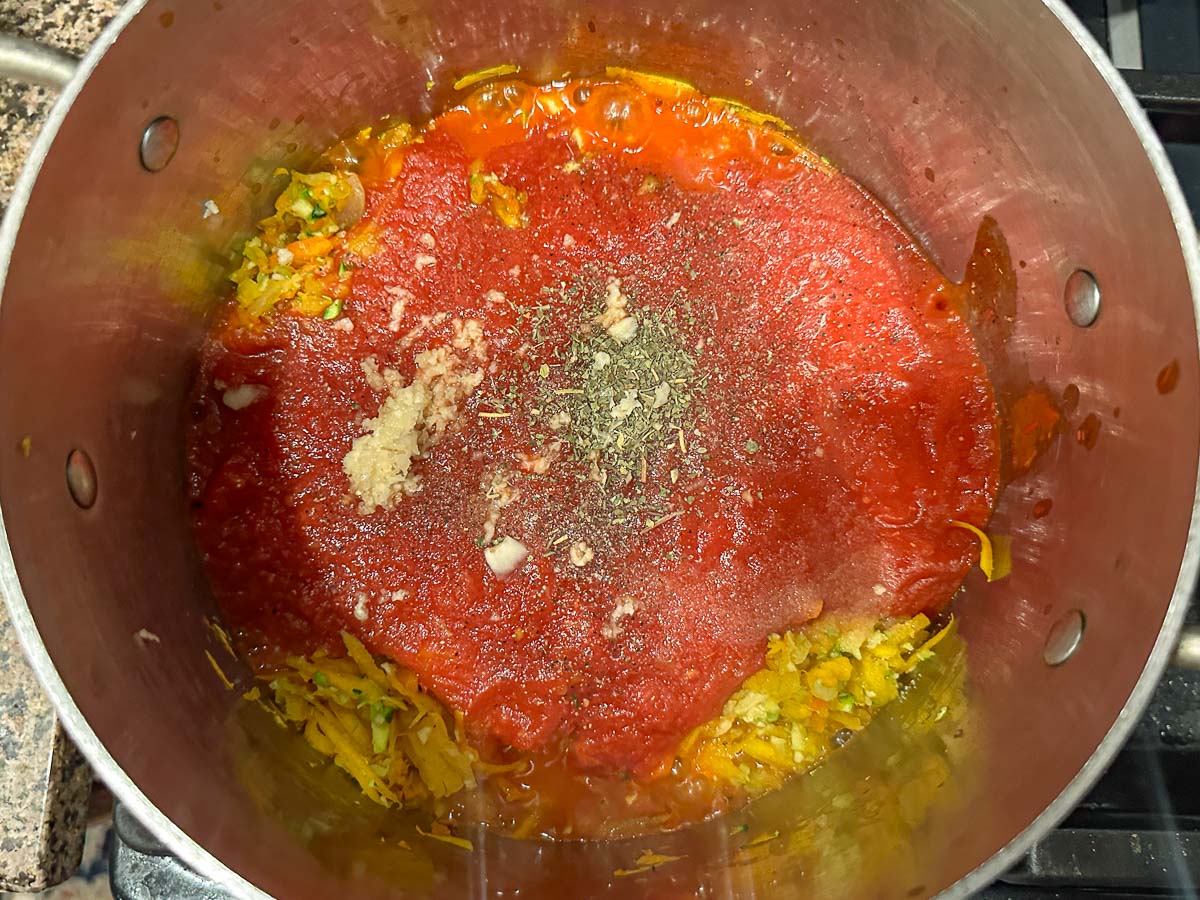 A stock pot with the crushed tomatoes and spices added.