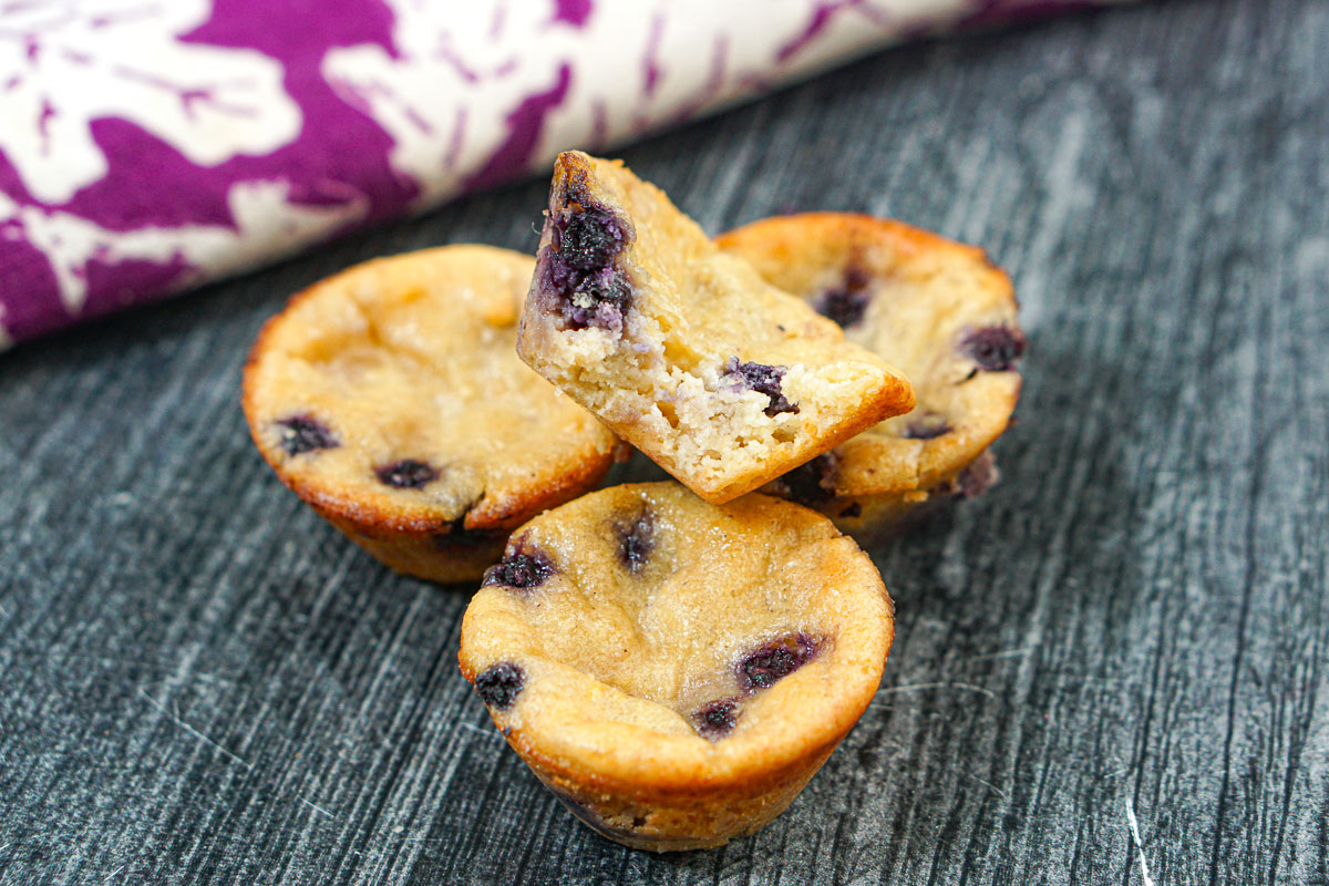 Four protein muffins and one with a bite taken out.