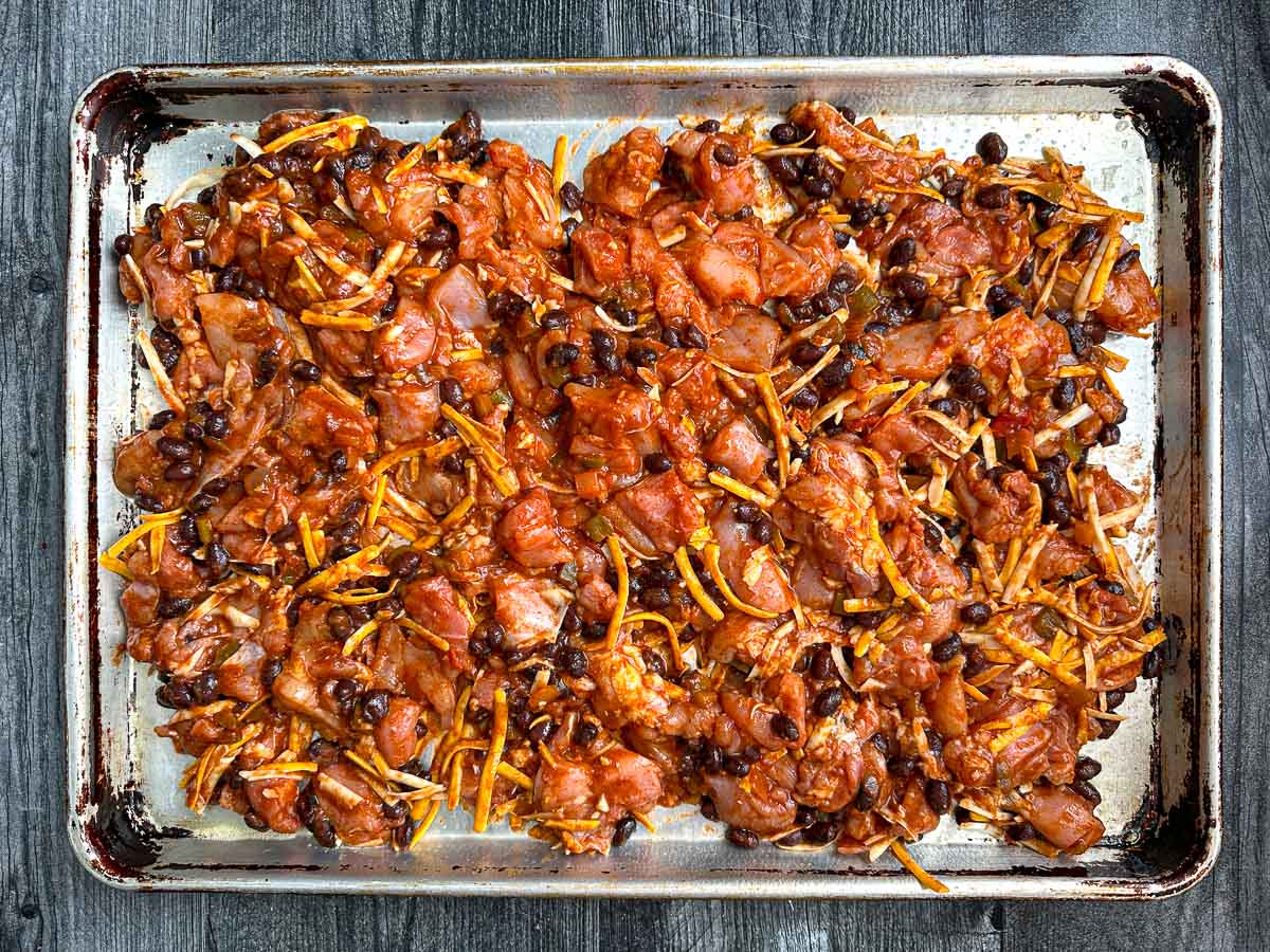 Sheet pan with with the raw filling chicken cheese burrito mixture ready to bake.