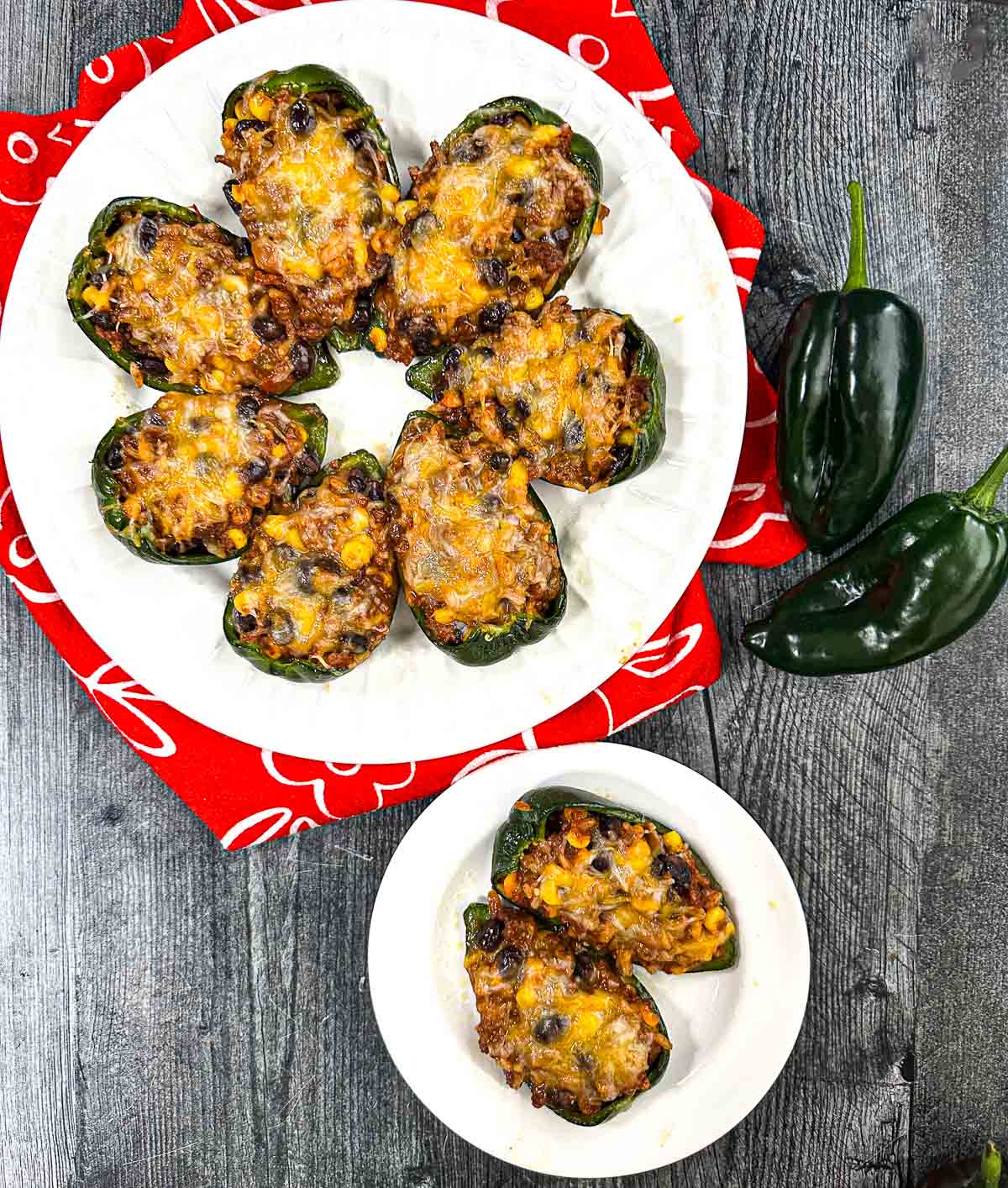 Aerial view of a white plate and platter with Mexican stuffed poblano peppers.