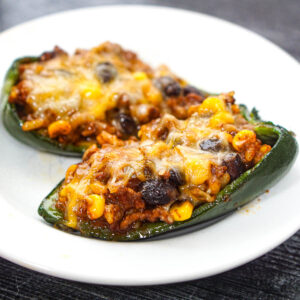 Closeup of a white plate with 2 Mexican stuffed poblanos.