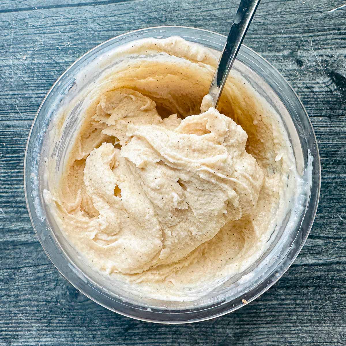 Aerial view of a pint of creamy keto egg nog ice cream and a spoon sticking out.