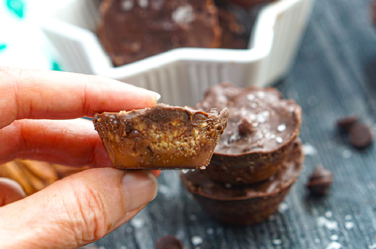 Fingers holding a piece of the toffee candy with a bit taken out.