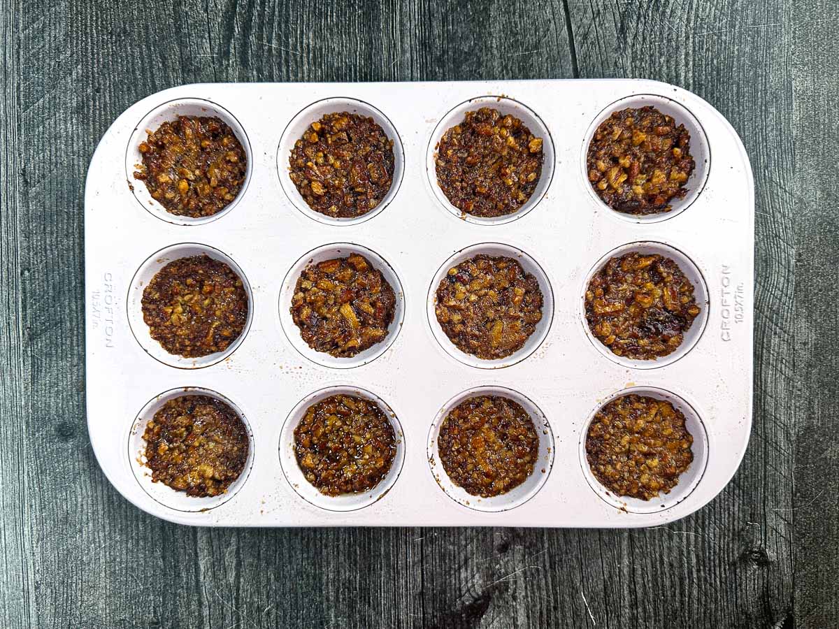 Muffin tin with the cooked nuts and sauce.
