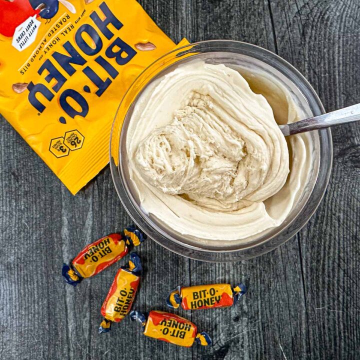 Aerial view of a pint container with keto bit o honey ice cream made in the Ninja Creami and some scattered candies next to i.