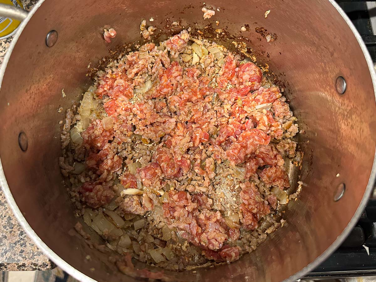 Pot with sausage browning with onions.