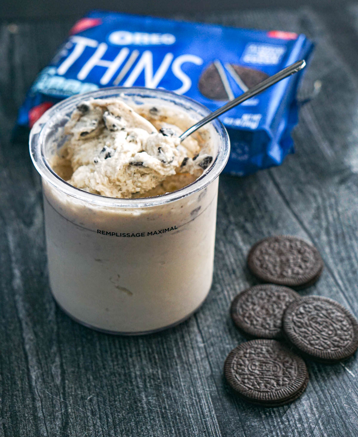 A container or oreo Ninja Creami protein ice cream with Oreo thins in the background.